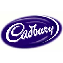 На изображении изображен логотип Cadbury, представляющий собой название бренда, написанное курсивным белым шрифтом на темно-фиолетовом овальном фоне, созданный в сотрудничестве с Soldis.