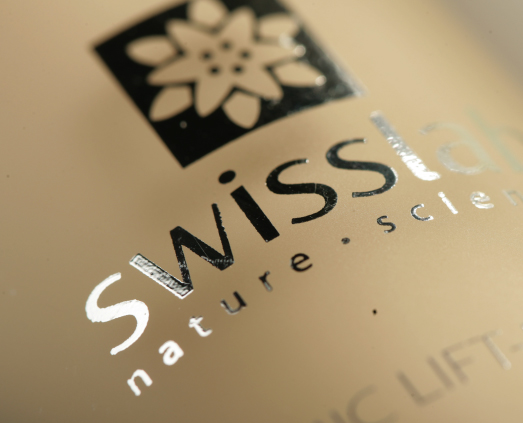 Крупный план этикетки продукта с названием бренда Swisslab черными и серебряными буквами, цветочным логотипом сверху и частично видимыми словами nature science в дизайне от Soldis